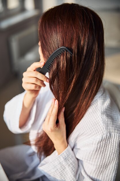 Close up of young female combing her hair