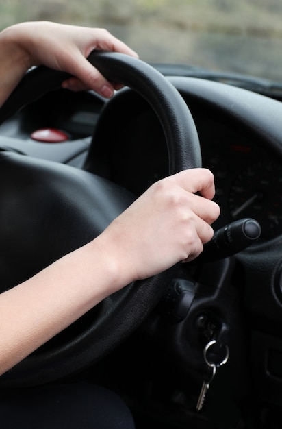 Close-up of a young female driver at the wheel 