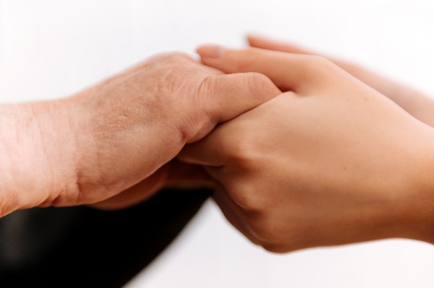 Close-up of a young female hand comforting the elderly hands of an old woman