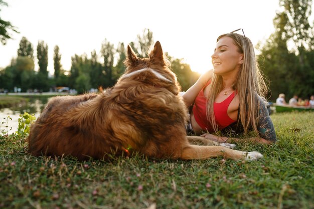 公園の芝生の上に座っている彼女の犬と若い女性のクローズアップ