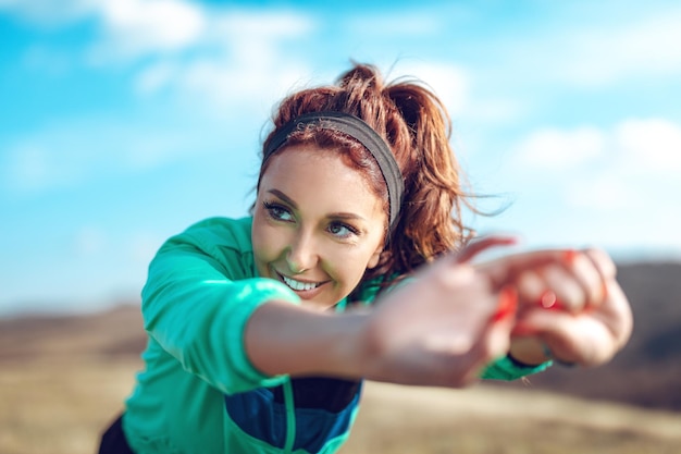 Close-up of a young fitness woman doing stretching exercise after jogging in the nature.