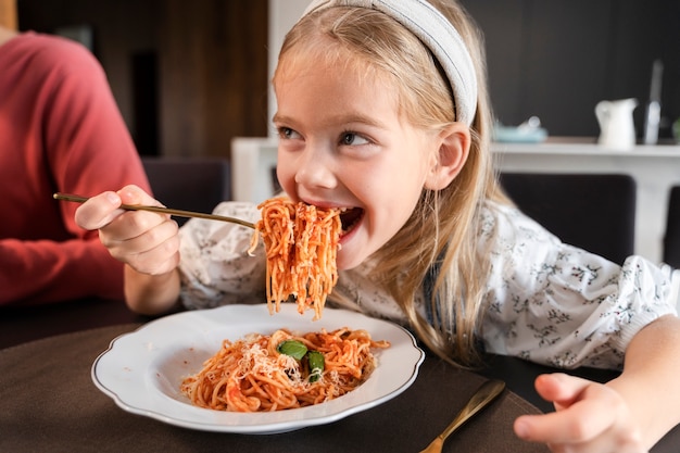 Photo close up on young girl eating pasta