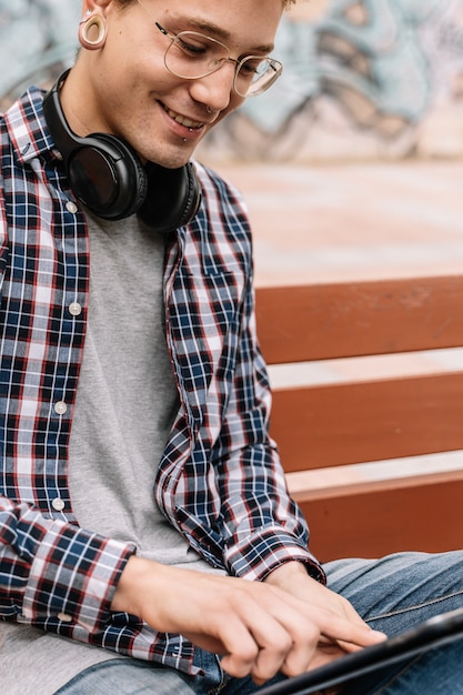 Close up of a young guy on a bench with headphones around neck