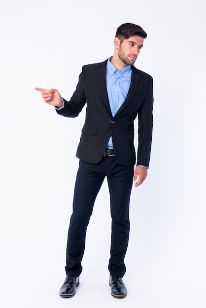 Close up of young handsome bearded Persian businessman in suit isolated