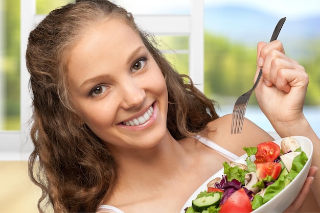 サラダを食べる若い幸せな女性のクローズアップ