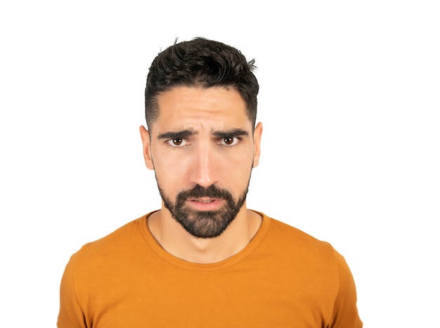 Close up of young latin man looking serious against white background in studio