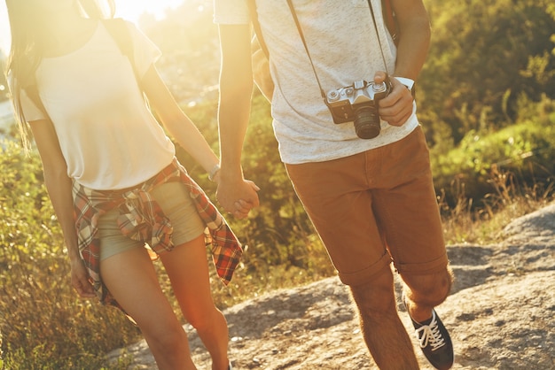 Close up of young loving couple in casual clothing holding hands while walking outdoors