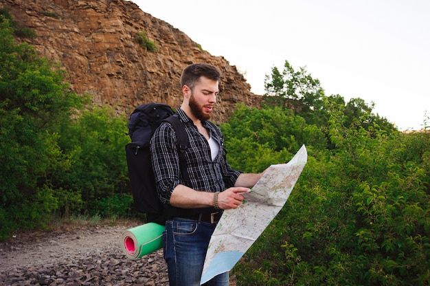 彼が一人で旅行-ライフスタイル、人々、アウトドア、休日のコンセプト-地図を読んで、若い男のクローズアップ。