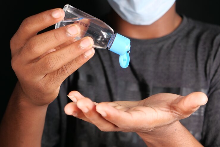 Photo close up of young man in face mask hand using sanitizer gel .