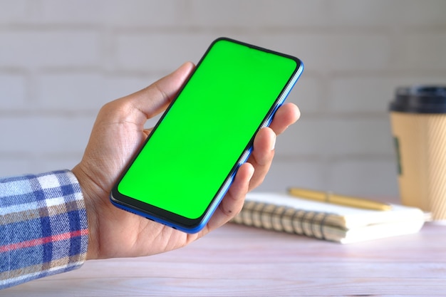 Close up of young man hand using smart phone with green screen