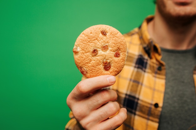 Close up young man holds cookie