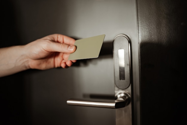 Close up, young man in hotel room is opening a door using a room key.