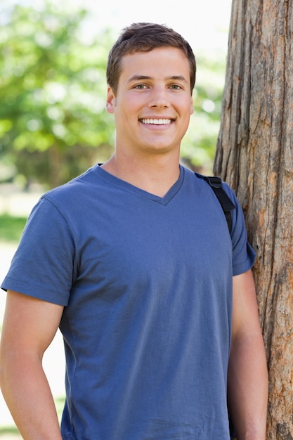 Close-up of a young man leaning against a tree