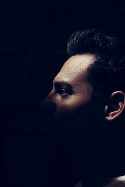 Photo close-up of young man looking away against black background