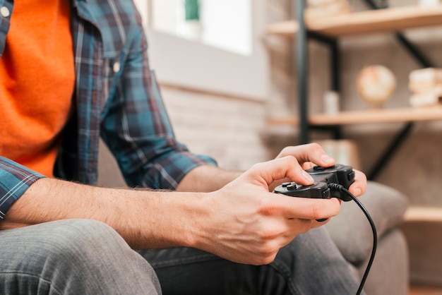 Foto primo piano di un giovane che gioca la console del gioco a casa