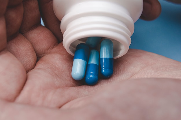 Close up young man pours the pills out of the bottle. Medicine and health care concept.