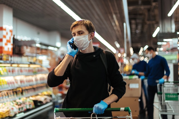 Close up young man in a protective mask talking on his smartphone