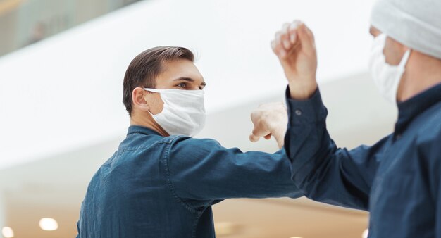 Close up. young man in a protective mask while welcoming his friend