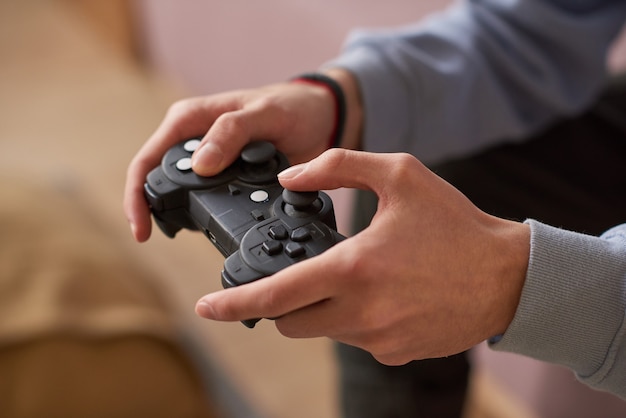 自宅でビデオゲームをプレイしながらジョイスティックのボタンを押す若い男のクローズアップ