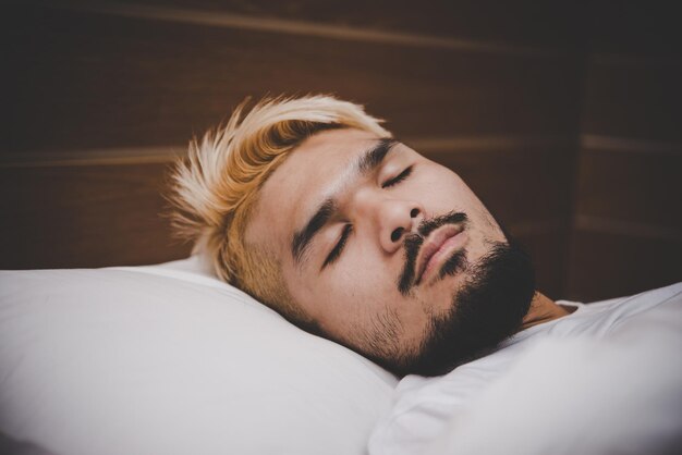 Photo close-up of young man sleeping on bed at home