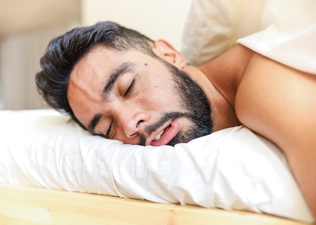 Close-up of a young man sleeping on bed