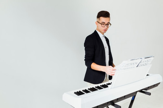 Close-up of a young man turning the pages of musical sheet on piano isolated on white background