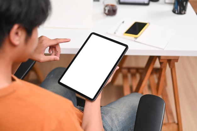 Close up over young man using digital tablet while sitting on office chair