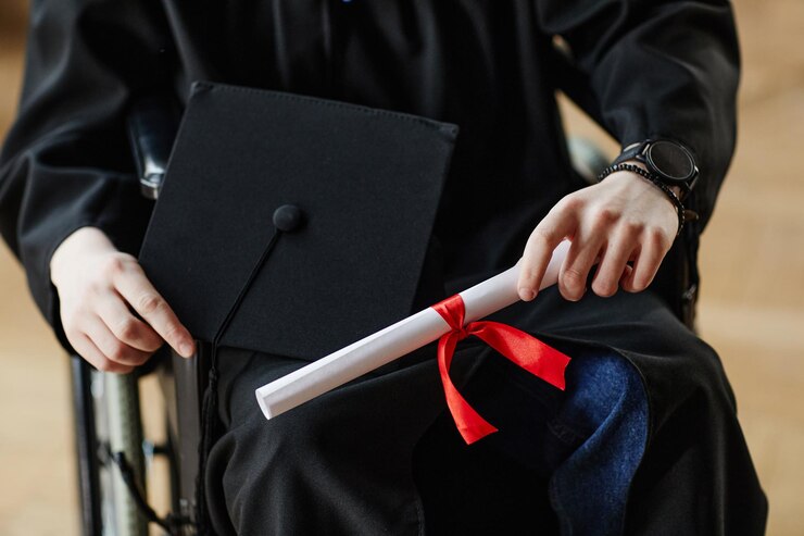 Close up of young man with disability at graduation ceremony in university holding diploma copy space