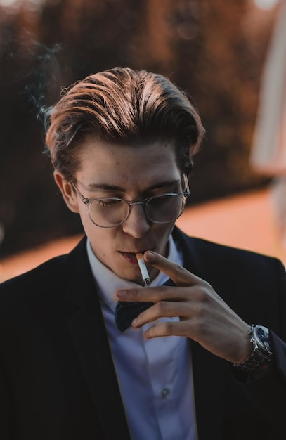 Photo close-up of young man with glasses smoking cigarette