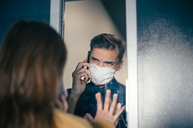 Photo close up. a young man and a woman are looking at each other anxiously through the glass. photo with a copy-space