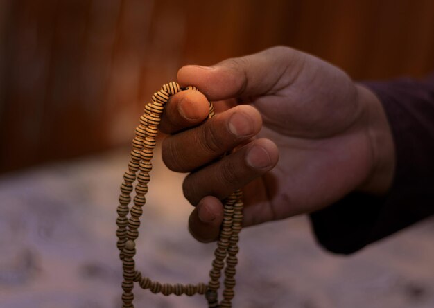 Close up young men praying and holding a wooden rosaryReligious asian muslim man holding rosary