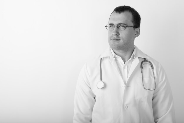 Close up of young muscular man doctor thinking while wearing eyeglasses