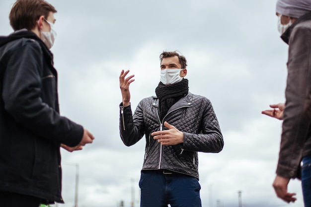 Close up young people in protective masks talk standing at a safe distance