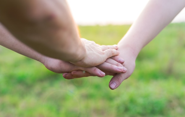 Primo piano dei giovani che uniscono le mani. gli amici che si tengono per mano mostrano solidarietà e lavoro di squadra.