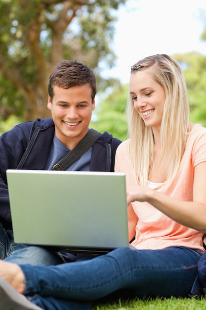 Close-up of young people sitting while using a laptop