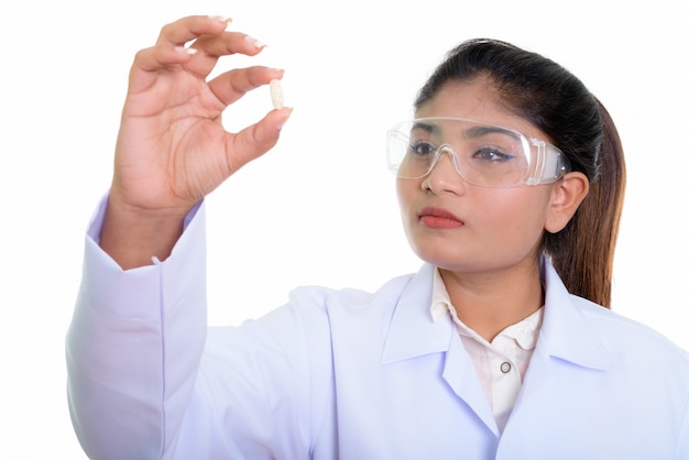 Close up of young Persian woman doctor looking at vitamin pill