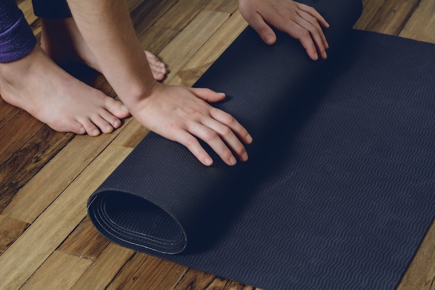 Close up of young person rolling her fitness mat