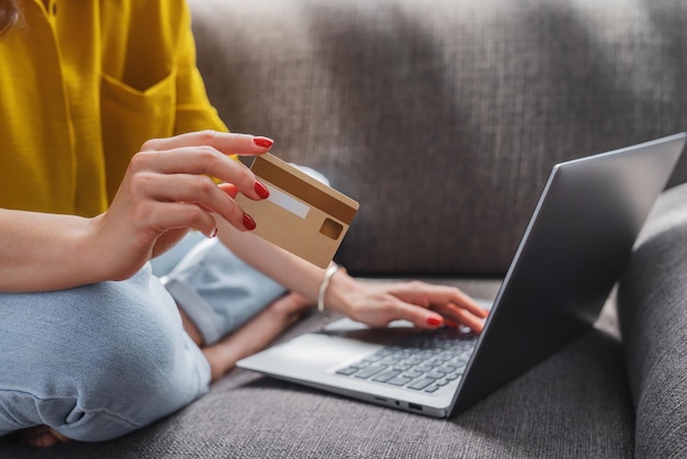 Close up of young pretty woman shopping using credit card and laptop at home