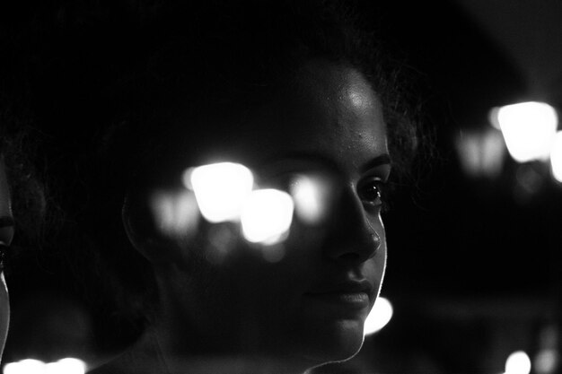 Close-up of young woman against illuminated light