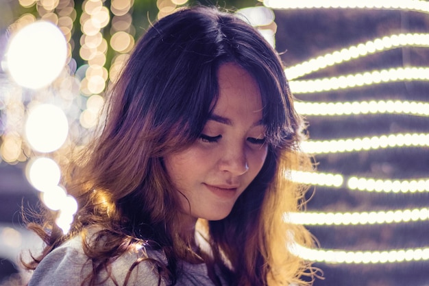 close-up of young woman amidst illuminated lights
