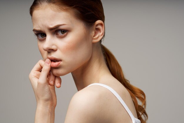 Close-up of young woman applying make-up against wall