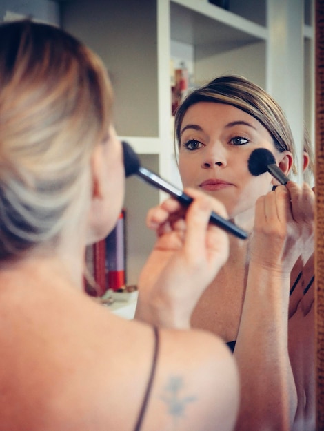 close-up of young woman applying make-up at home