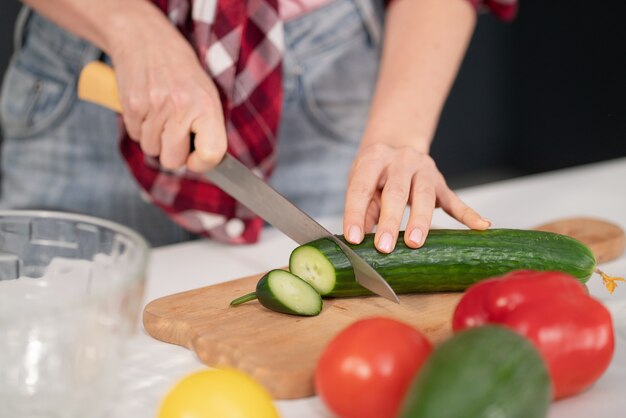 閉じる。台所に立って昼食や夕食を調理するテーブルで食材を切る若い女性