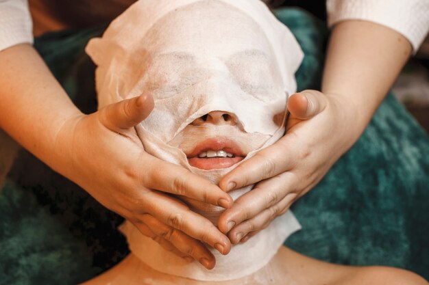 Закройте молодой женщины, делающей процедуры по уходу за кожей лица в оздоровительном спа-центре.