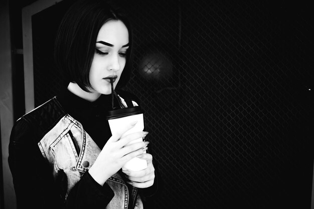 Close-up of young woman drinking coffee by fence