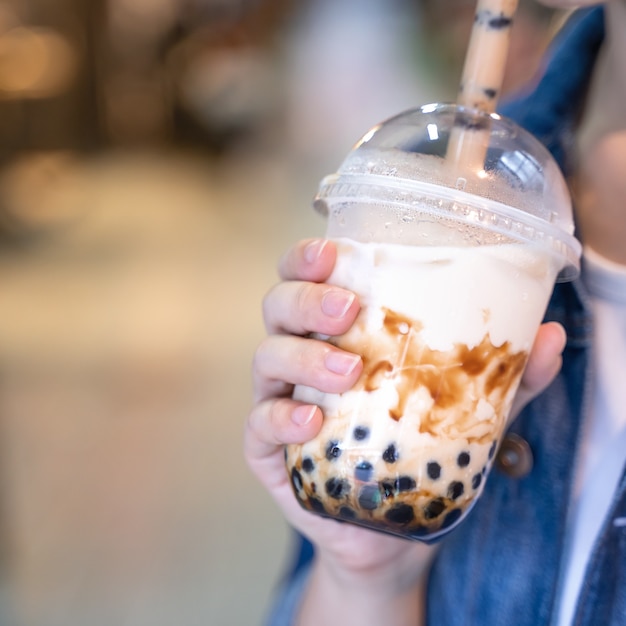 Close up of young woman drinking a cup of tapioca pearl bubble milk tea