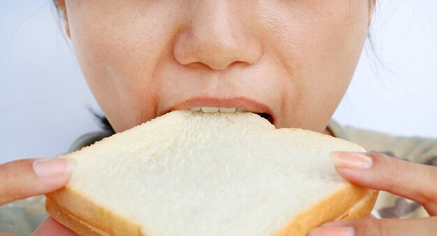 Close up young woman eating bread.