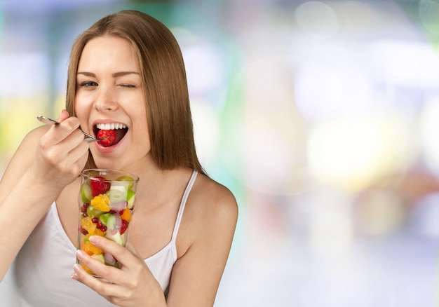 Foto primo piano di una giovane donna che mangia macedonia di frutta