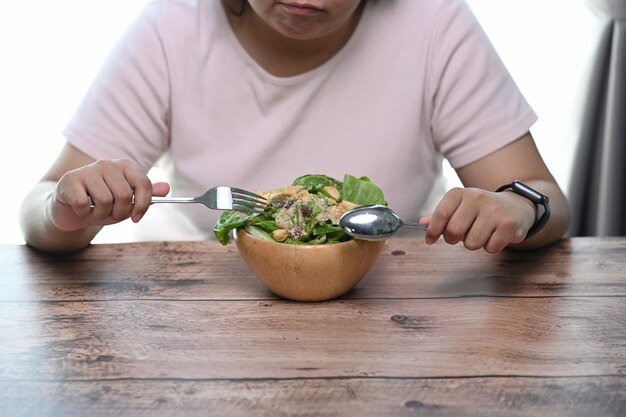 Close up on young woman eating salad at home