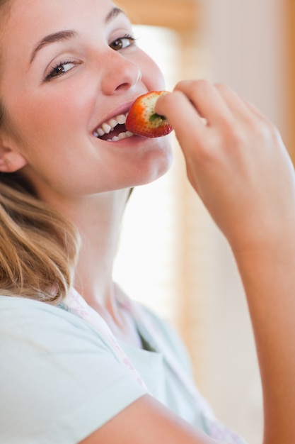 Foto chiuda in su di una giovane donna che mangia una fragola